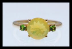 A hallmarked 9ct gold ring prong set with a brilliant cut yellow opalescent stone flanked with two