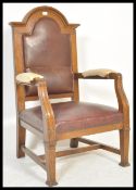 A 20th Century oak judges or judge arm chair having red leather upholstery and a domed top back