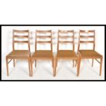 A set of four retro 20th Century teak wood rail back dining chairs, upholstered seat pads raised