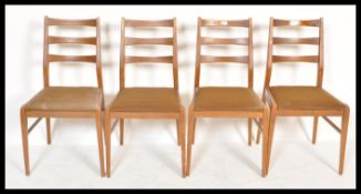 A set of four retro 20th Century teak wood rail back dining chairs, upholstered seat pads raised