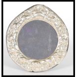 A sterling silver easel back photograph picture frame of circular form having rococo style relief