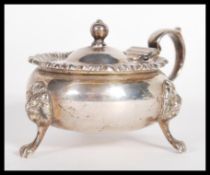 An early 20th Century hallmarked silver large lidded mustard pot raised on lion mask paw feet with