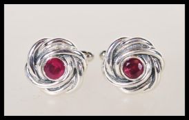 A pair of sterling silver cufflinks of knot design having central rubies / faceted ruby stones.