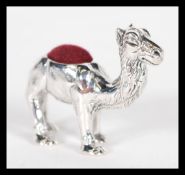 A sterling silver pincushion in the form of a camel having red baize pin cushion to top. Weighs 17