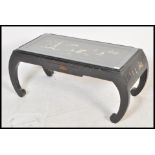A Chinese black lacquer coffee table raised on scrolled legs with single drawer to front having