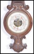 An early 20th Century oak barometer and carved scroll work. The enamel dial having painted details