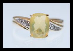 A hallmarked 9ct gold ring prong set with a rectangular yellow stone with white accent stones to the