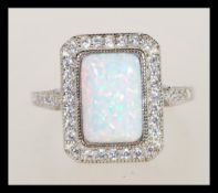 A sterling silver Art Deco style ring having a central opal panel and decorated with CZ stones.