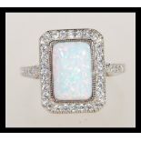 A sterling silver Art Deco style ring having a central opal panel and decorated with CZ stones.