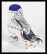 A sterling silver pin cushion in the form of a roller skate having purple pin cushion atop. Weighs