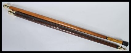Two 20th Century walking stick canes with wooden shafts having carved decoration with brass orb