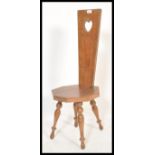 A early 20th century spinning chair raised on turned legs having a pierced heart handle to the