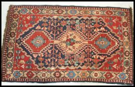 A 20th Century wool Persian floor carpet rug having red and blue ground with central medallion and