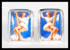 A pair of sterling silver cufflinks set with enamel pictorial panels depicting a pin up girl. Weighs