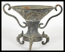 A 19th Century Chinese bronze twin handled pedestal oil burner, raised on tripod scroll feet with
