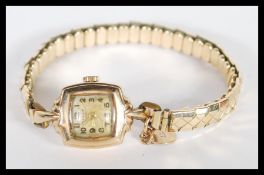 A 9ct gold ladies cocktail dress watch set to a rolled gold expanding bracelet. The watch with