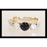 A stamped 18ct gold ring prong set with a round cut sapphire flanked by two brilliant cut