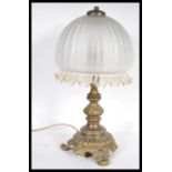 An early 20th Century heavy brass table lamp of scrolled form having a bulbous frosted glass