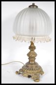 An early 20th Century heavy brass table lamp of scrolled form having a bulbous frosted glass