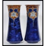 A pair of early 20th Century Royal Doulton tapering cylindrical stoneware vases decorated with Art