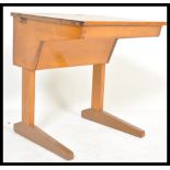 A late Victorian beech wood childs school desk being raised on shaped leg supports with sloped