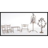 A collection of silver dolls house miniature furniture to include a table and chairs having a turned