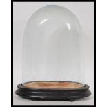 A 20th Century glass dome cloche on an ebonised wooden pedestal base. Measures 27cm high by 20cm