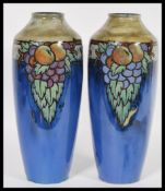 A Royal Doulton pair of stoneware vases on a mottled blue ground decorated with fruit, impressed