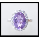 A stamped 925 silver ladies dress dring set with a large faceted amethyst stone with a halo with