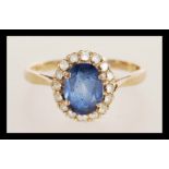 A hallmarked 9ct gold ring prong set with an oval cut synthetic sapphire set with a halo of white