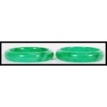 A true pair of 20th Century Chinese green jade bangle bracelets of circular form in a deep green