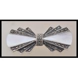 A silver Art Deco style brooch in the form of a bow tie set with marcasites and mother of pearl