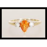 A hallmarked 9ct gold ladies dress ring set with a tear drop cut orange stone flanked by two white