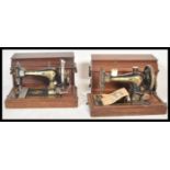 Two early 20th century hand crank Singer sewing machines, both machines with wooden carry cases and