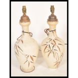 A pair of early 20th Century ceramic table lamp vases having hand painter floral sprays and