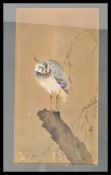 A 20th Century Japanese painting on wood depicting a heron standing on a log with branches behind.