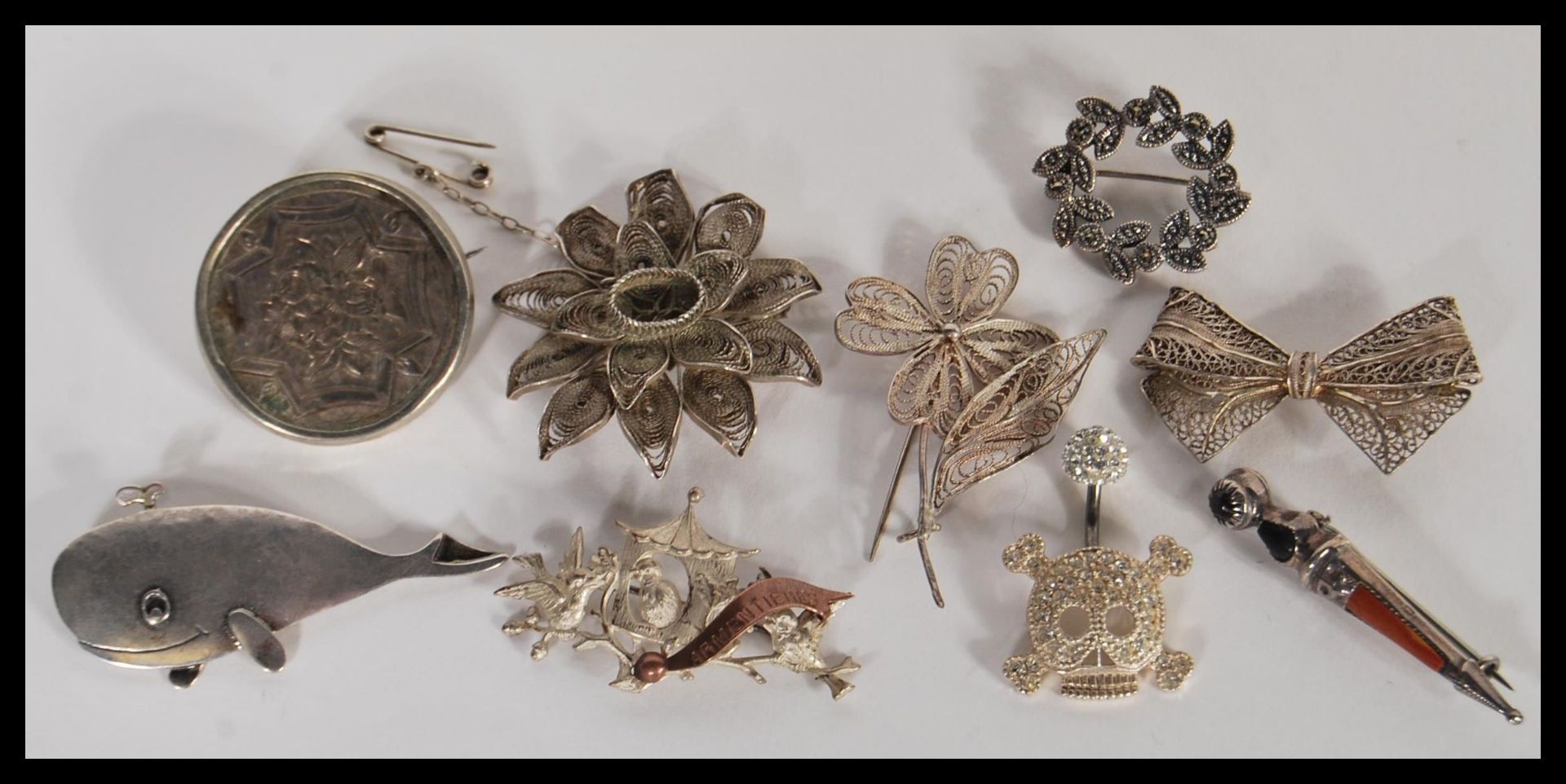 A group of eight silver brooches to include filigree flower and bow examples, marcasite leaf
