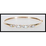A 9k stamped 9ct gold bangle bracelet set with illusion set diamonds and faceted prong set blue