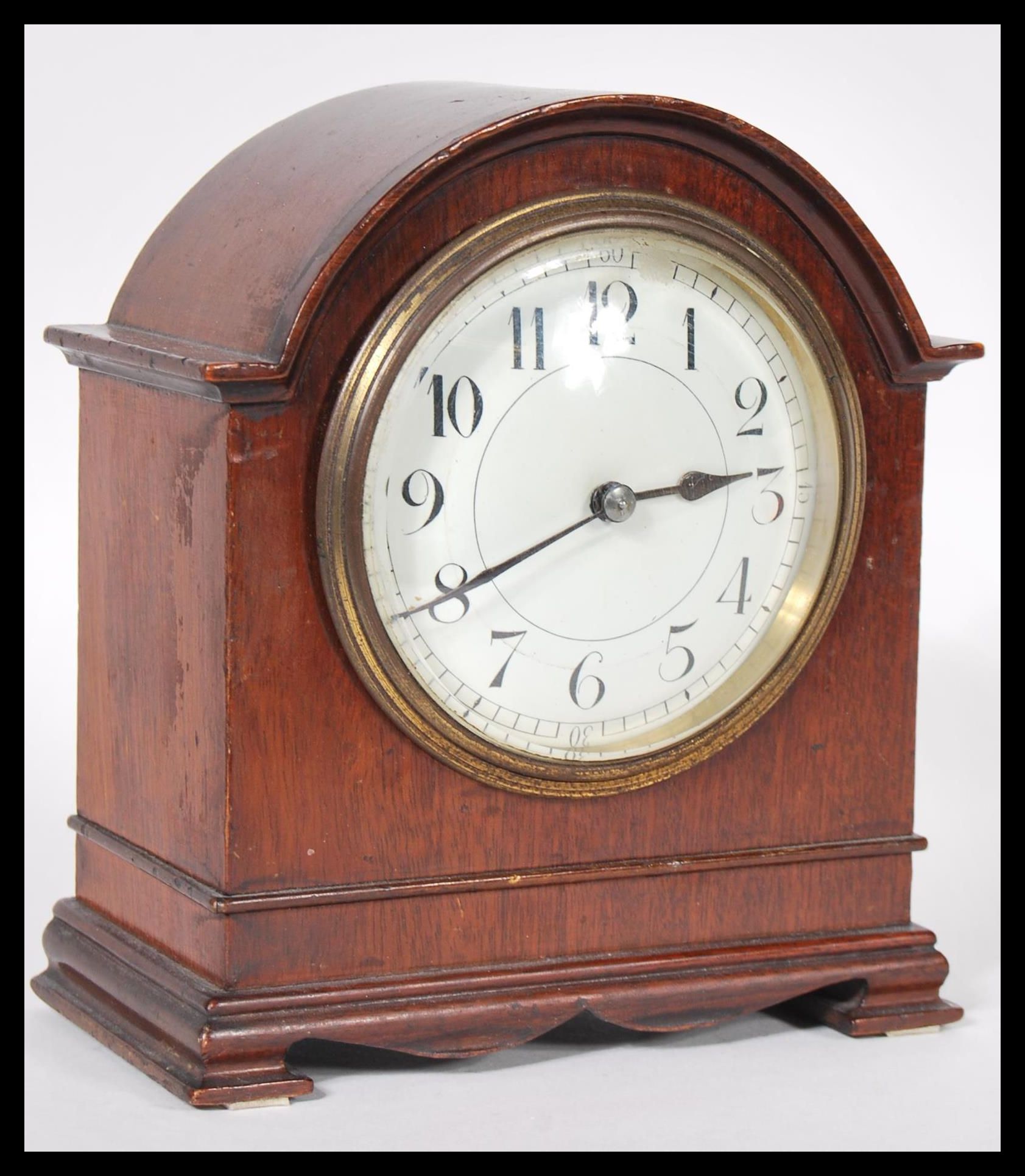 A 20th Century mantel clock having a mahogany case of domed form with a round white enamelled