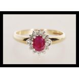 A hallmarked 9ct gold diamond and garnet flower head ring having a central faceted red stone with