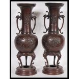 A pair of 19th century Japanese bronze vases of baluster form having twin scrolled handles with