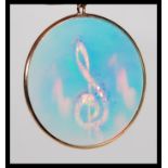 A 9ct gold roundel pendant inset with hologram of musical notes together with a 9ct chain.  The