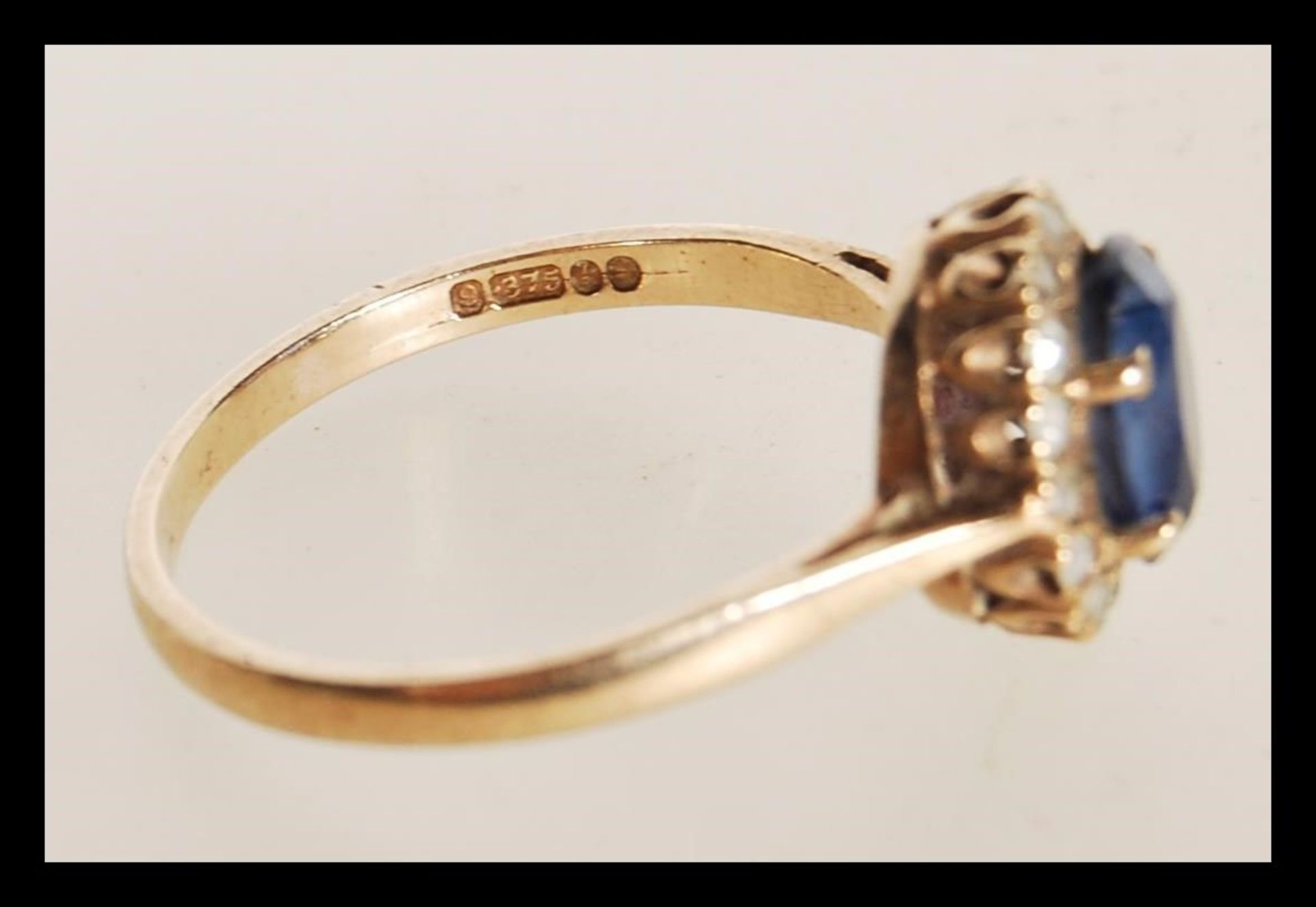 A hallmarked 9ct gold ring prong set with an oval cut synthetic sapphire set with a halo of white - Bild 4 aus 4