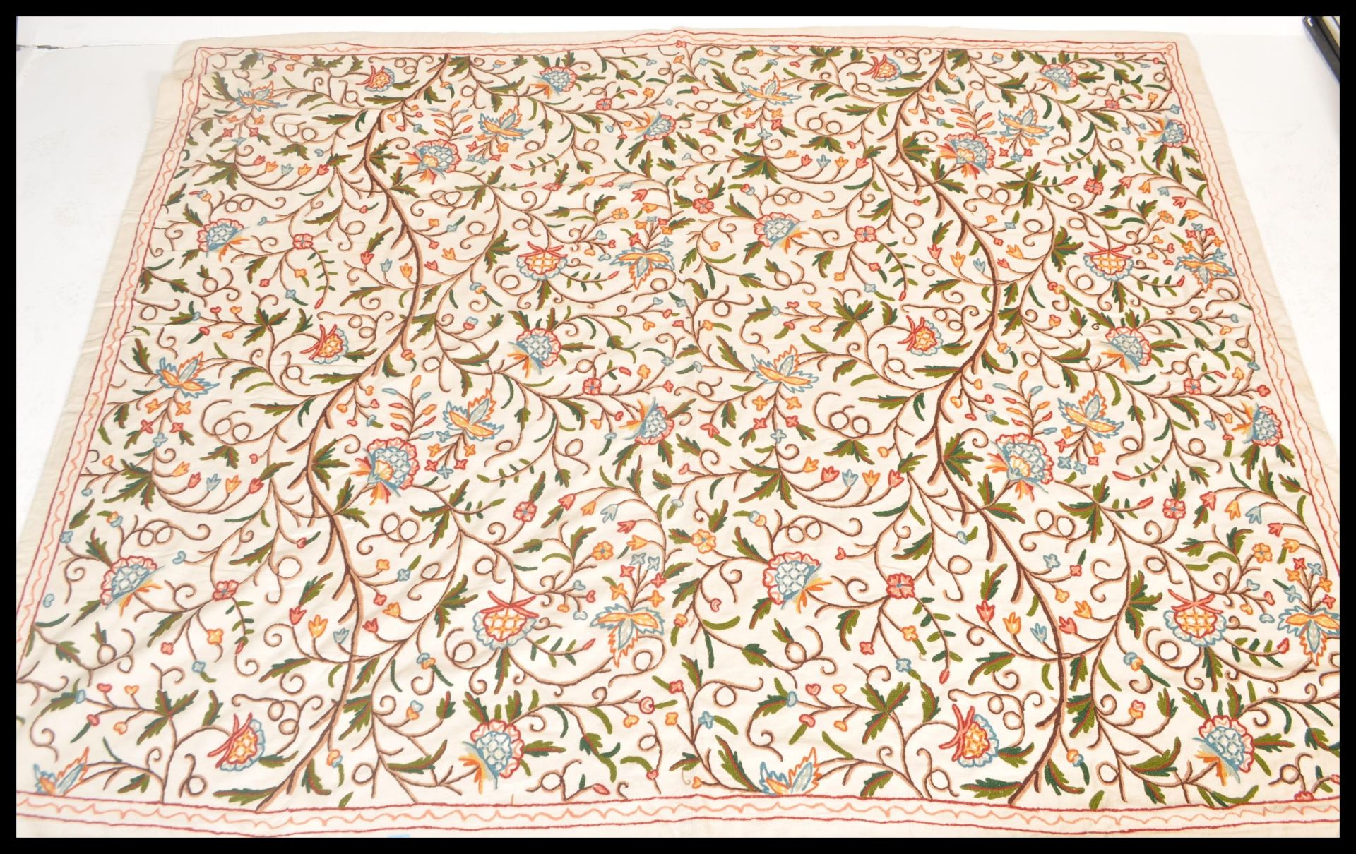 A 20th Century embroidered crewel work throw blanket on a woven white fabric ground with embroidered