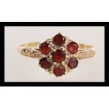 A stamped 9ct gold ring having a flower head set with seven round garnet stones. Weight 2.1g. Size