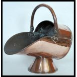 A 19th Century Victorian copper coal scuttle of helmet form raised on conical pedestal base with