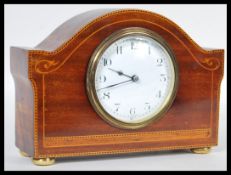 An early 20th Century French mahogany mantel clock having inlay decoration. The white enamel face