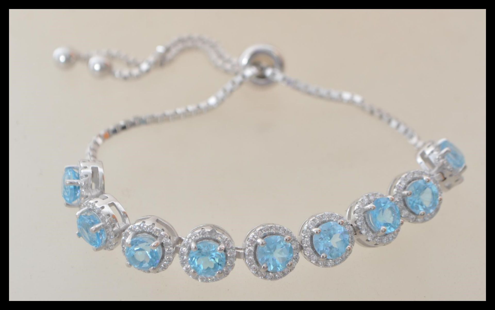 A stamped 925 silver bracelet having round panels set with cz's and blue topaz stones. Weight 10.3g.