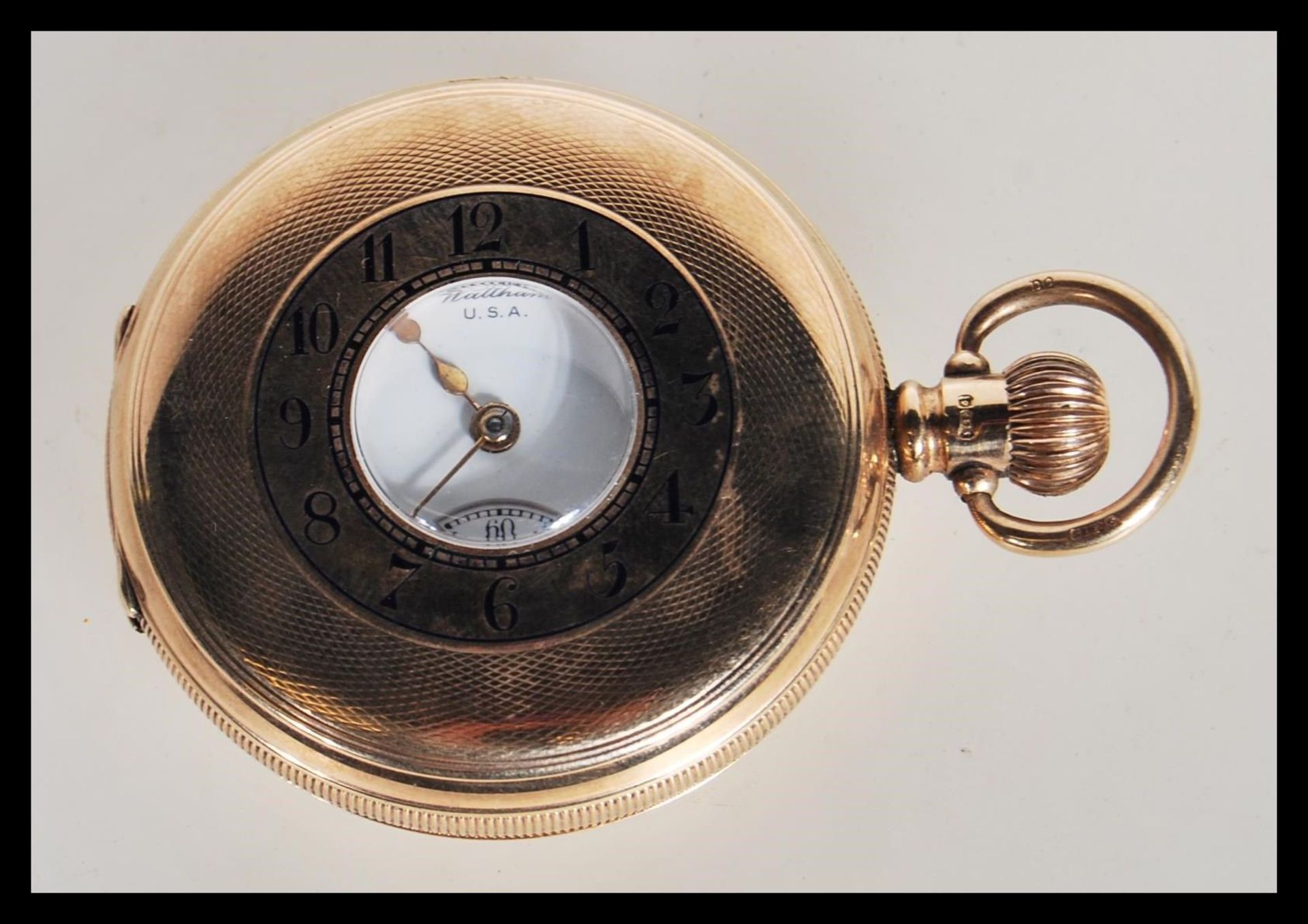 A hallmarked 9ct gold half hunter pocket watch by Waltham USA having a white enamelled dial with