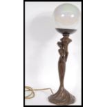 An Art Nouveau bronze effect table lamp in the form of a maiden holding a large globular